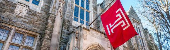 Image of Temple University building with a Temple University flag hanging.